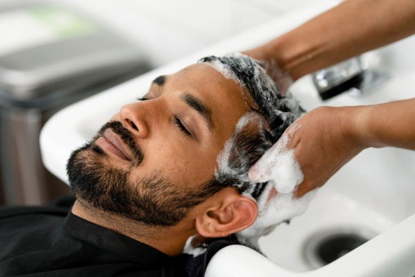 Hombre al cual le están lavando el cabello